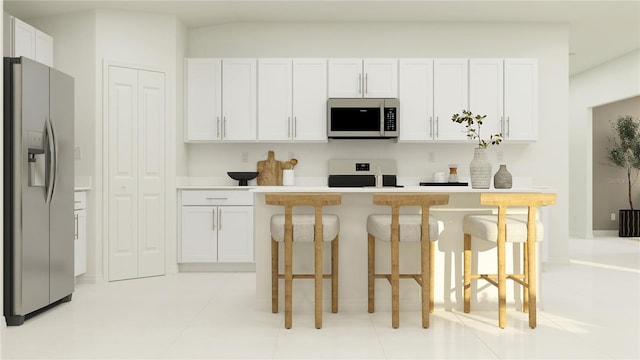 kitchen with stainless steel appliances, a kitchen bar, light countertops, and white cabinets