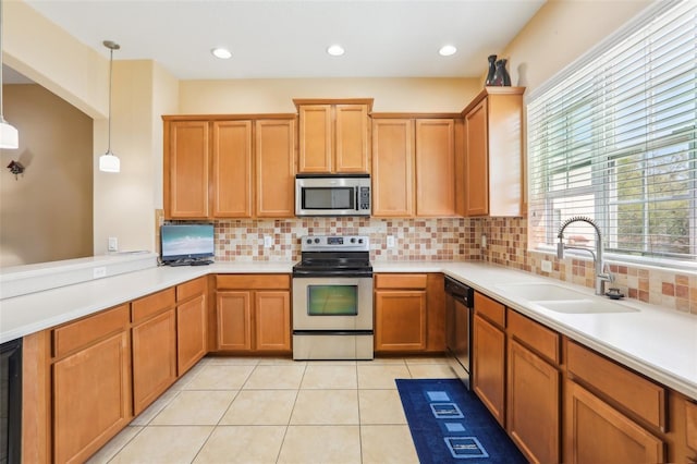 kitchen with light tile patterned floors, light countertops, decorative backsplash, appliances with stainless steel finishes, and a sink