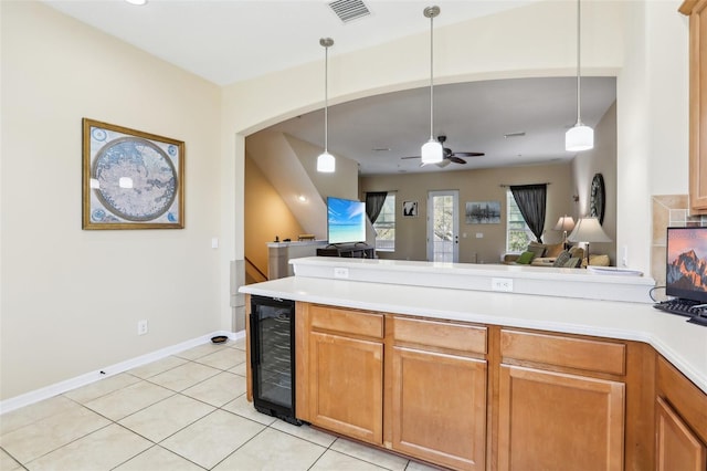 kitchen featuring beverage cooler, a peninsula, visible vents, open floor plan, and decorative light fixtures