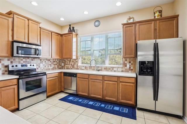 kitchen with light tile patterned floors, decorative backsplash, stainless steel appliances, light countertops, and a sink