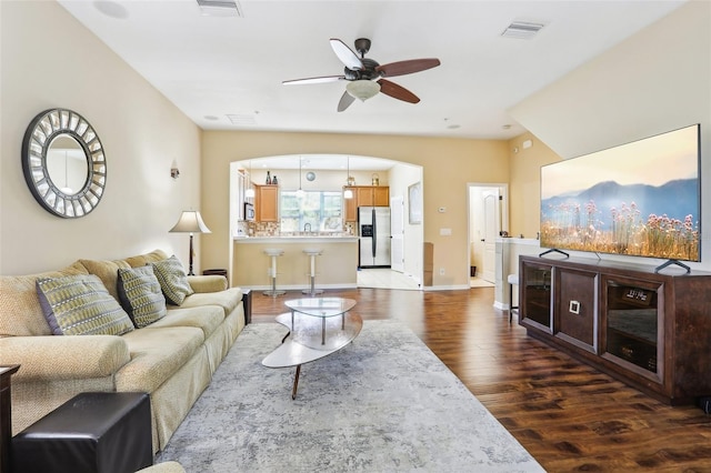 living area featuring baseboards, wood finished floors, visible vents, and a ceiling fan