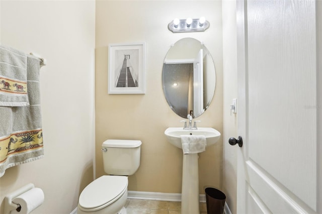 bathroom featuring toilet, baseboards, a sink, and tile patterned floors