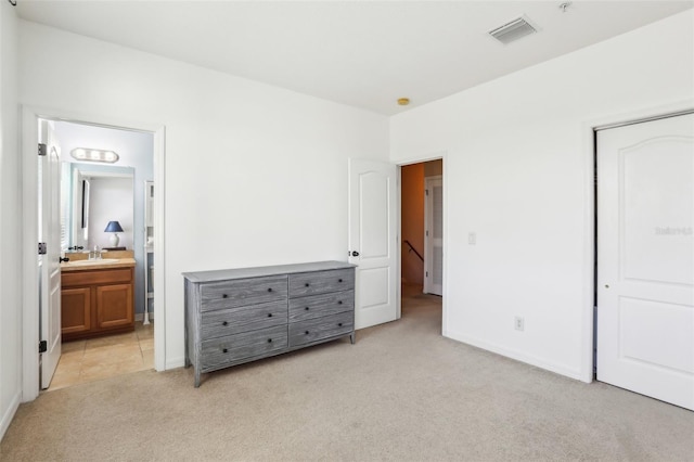 bedroom featuring connected bathroom, light carpet, a sink, visible vents, and baseboards