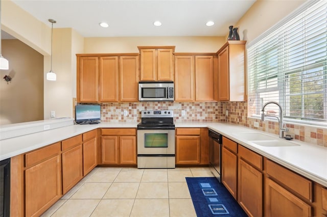 kitchen with tasteful backsplash, light tile patterned floors, a sink, light countertops, and appliances with stainless steel finishes