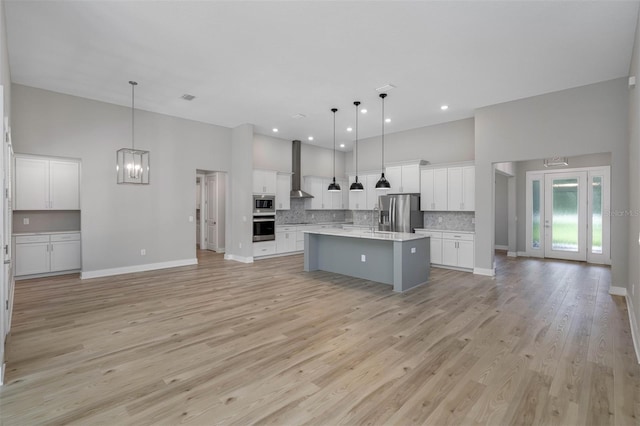 kitchen with open floor plan, appliances with stainless steel finishes, backsplash, and a high ceiling