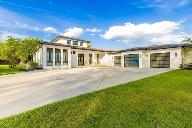 prairie-style house with a garage, concrete driveway, a front lawn, and stucco siding