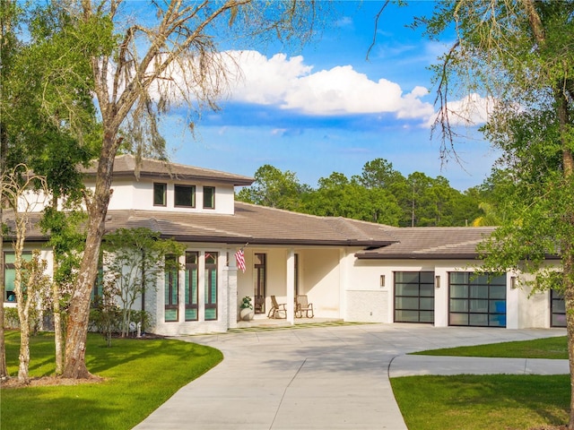 view of front of home with a garage, driveway, a front yard, and stucco siding