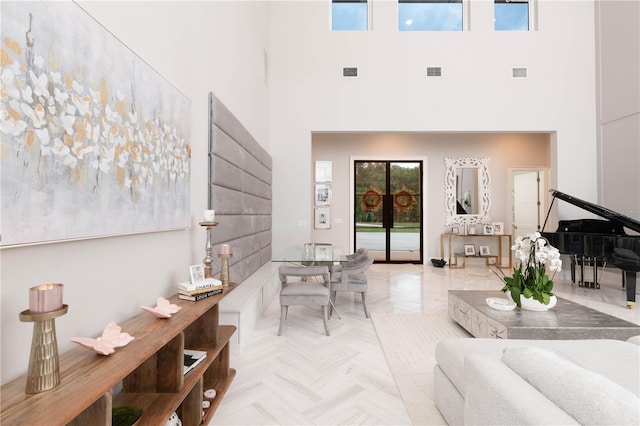 living area with visible vents and a towering ceiling