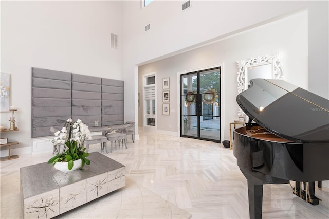 sitting room featuring a towering ceiling, visible vents, and baseboards