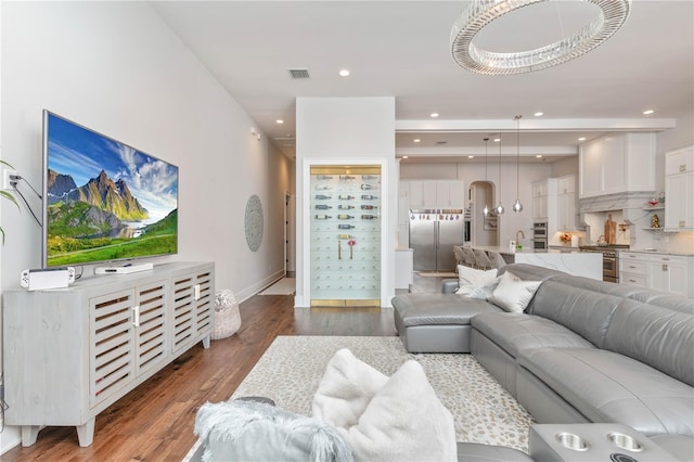 living room with recessed lighting, visible vents, baseboards, and wood finished floors