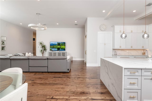 kitchen with light stone countertops, backsplash, open floor plan, white cabinetry, and wood finished floors