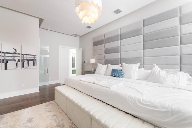 bedroom with wood finished floors, visible vents, and baseboards