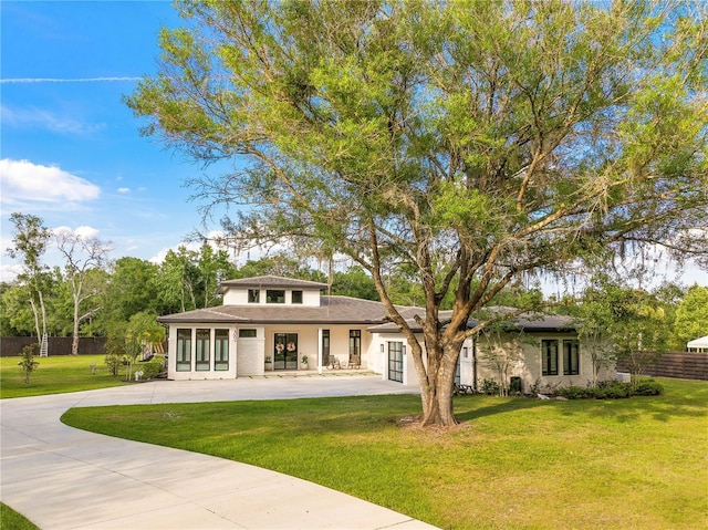 rear view of property featuring a yard, concrete driveway, and fence