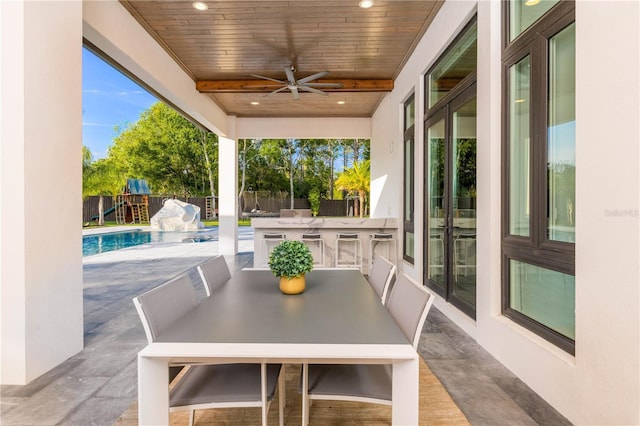 view of patio / terrace featuring a fenced in pool, a ceiling fan, exterior kitchen, outdoor wet bar, and a fenced backyard