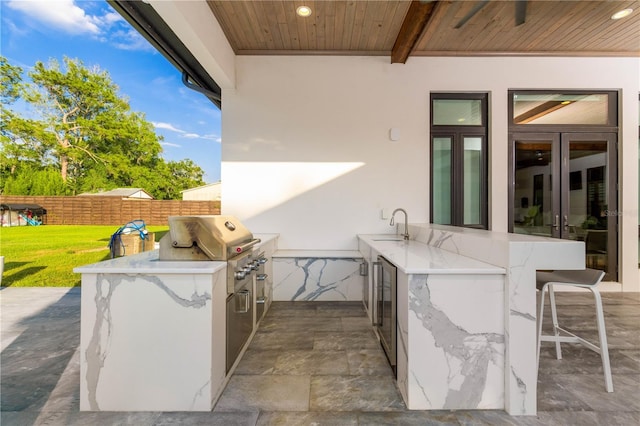 view of patio featuring exterior kitchen, fence, grilling area, and a sink