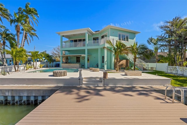 rear view of house featuring a fenced backyard, a balcony, stairway, a fenced in pool, and a patio area