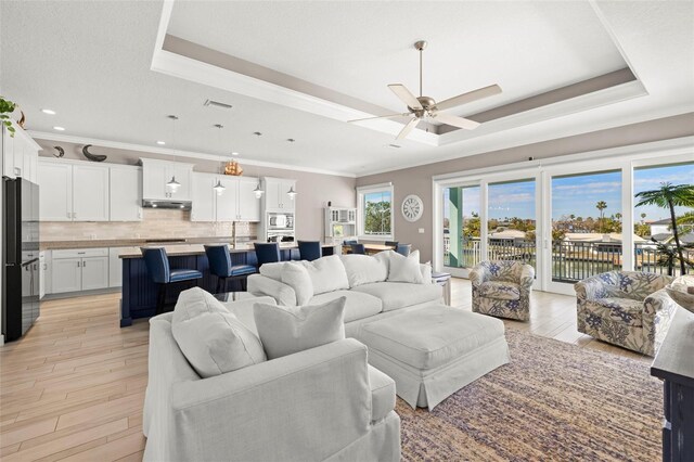 15904 Redington Dr, Redington Beach, FL 33708 - living room with light wood-type flooring, a raised ceiling, a ceiling fan, and crown molding