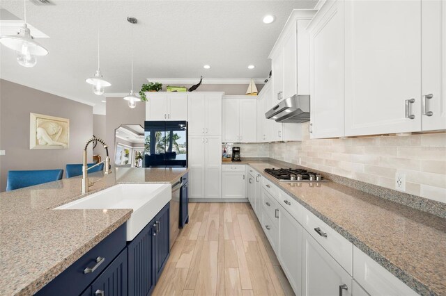 15904 Redington Dr, Redington Beach, FL 33708 - kitchen with white cabinets, under cabinet range hood, blue cabinetry, stainless steel gas cooktop, and backsplash