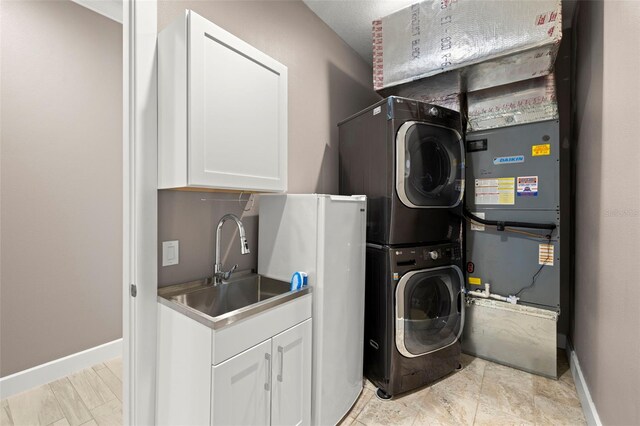 15904 Redington Dr, Redington Beach, FL 33708 - washroom with stacked washer / drying machine, cabinet space, a sink, and baseboards