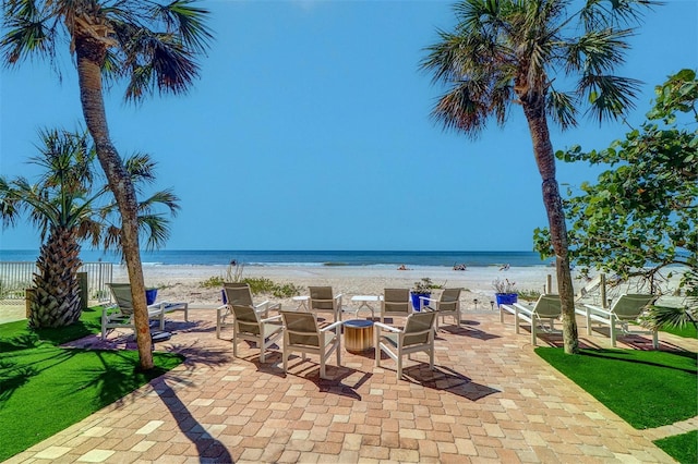 view of patio / terrace featuring a water view and a beach view