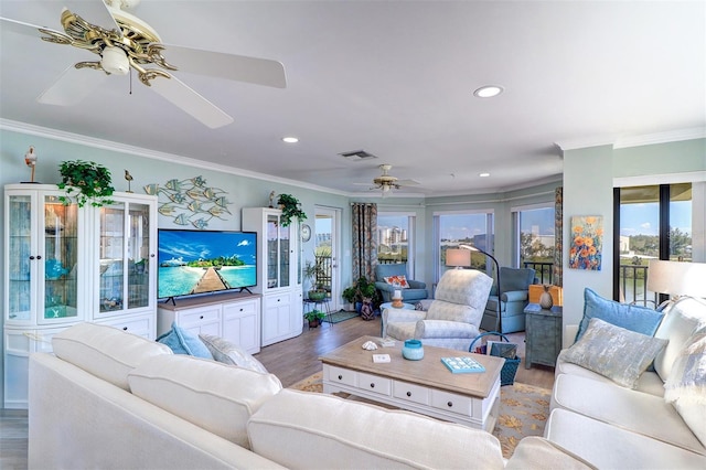 living area featuring visible vents, wood finished floors, ceiling fan, and crown molding