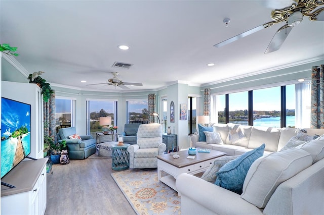 living room featuring visible vents, a healthy amount of sunlight, a ceiling fan, and crown molding