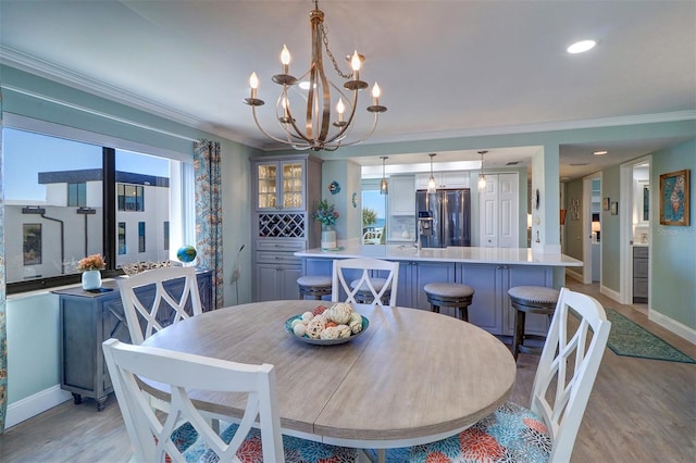 dining area with baseboards, an inviting chandelier, recessed lighting, light wood-style floors, and crown molding