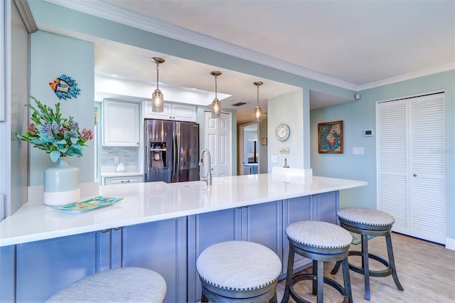 kitchen with light wood finished floors, a peninsula, stainless steel fridge with ice dispenser, ornamental molding, and a sink