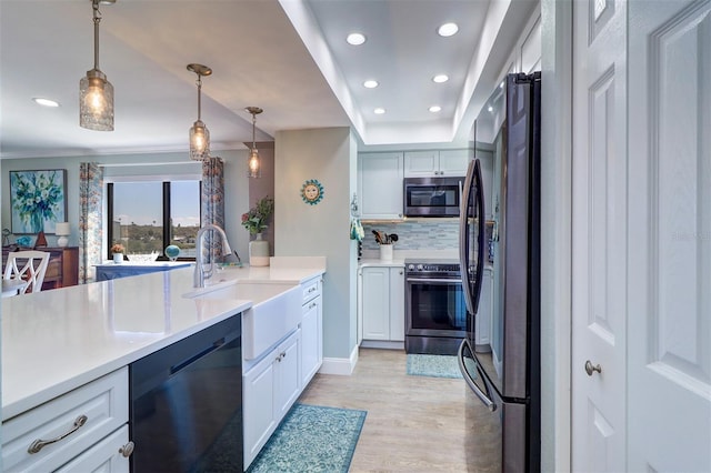 kitchen featuring a sink, decorative backsplash, white cabinets, appliances with stainless steel finishes, and light wood-type flooring