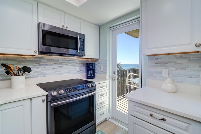 kitchen with decorative backsplash, white cabinets, appliances with stainless steel finishes, and light countertops