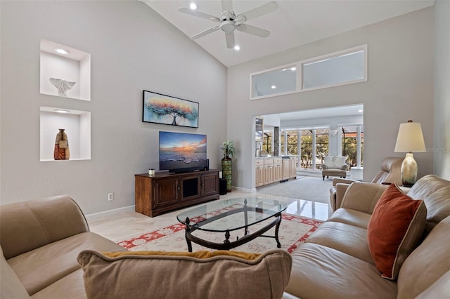 living area featuring ceiling fan, high vaulted ceiling, marble finish floor, and baseboards