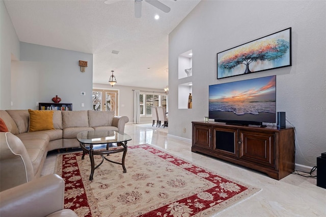 living room featuring marble finish floor, a towering ceiling, a ceiling fan, and baseboards