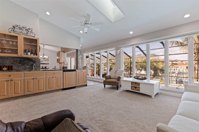 living room featuring high vaulted ceiling, recessed lighting, light carpet, ceiling fan with notable chandelier, and a skylight