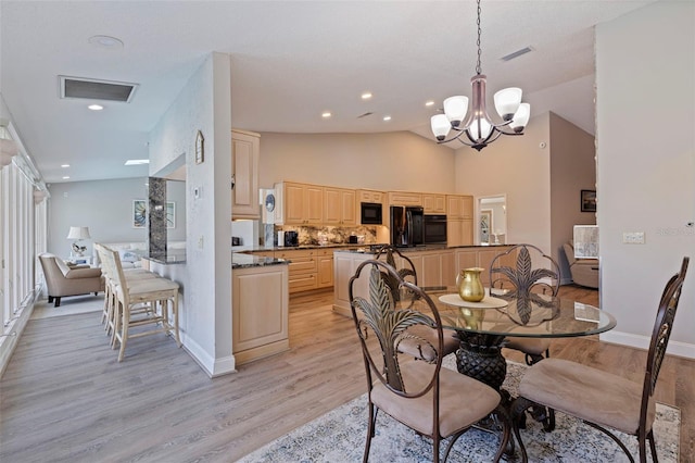 dining room with lofted ceiling, light wood finished floors, a chandelier, and visible vents