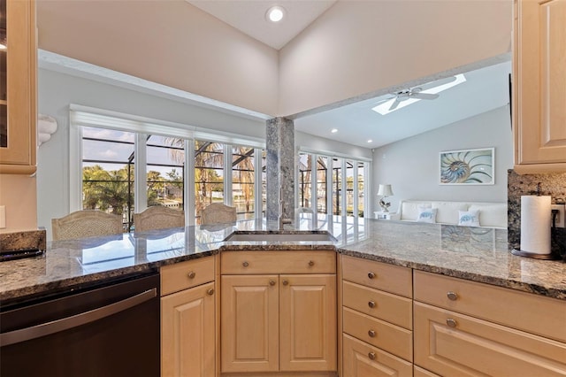 kitchen featuring light stone counters, light brown cabinets, a ceiling fan, vaulted ceiling, and stainless steel dishwasher