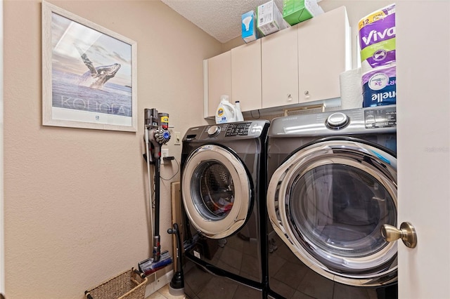 washroom with cabinet space, tile patterned floors, a textured ceiling, and washing machine and clothes dryer