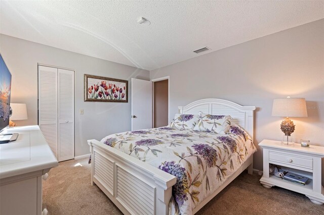 bedroom with a textured ceiling, light carpet, visible vents, baseboards, and a closet