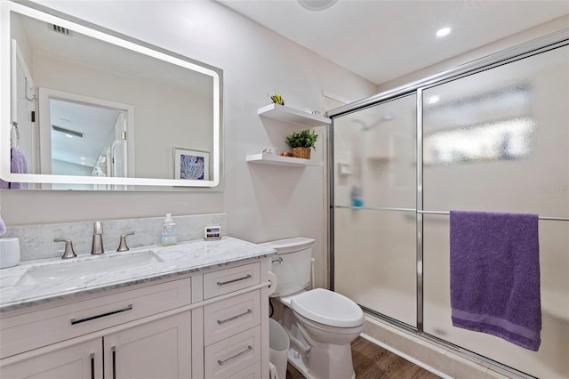 bathroom with a stall shower, vanity, toilet, and wood finished floors