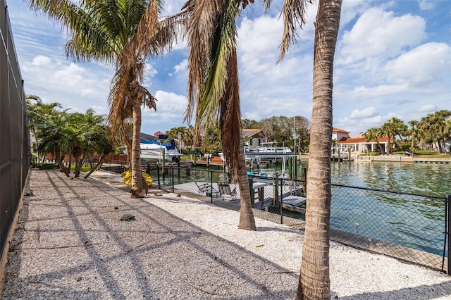 water view with boat lift, a boat dock, and fence