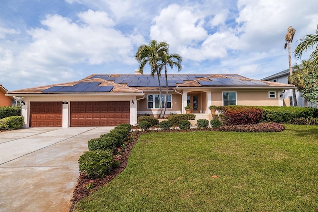 ranch-style house featuring an attached garage, driveway, stucco siding, roof mounted solar panels, and a front yard