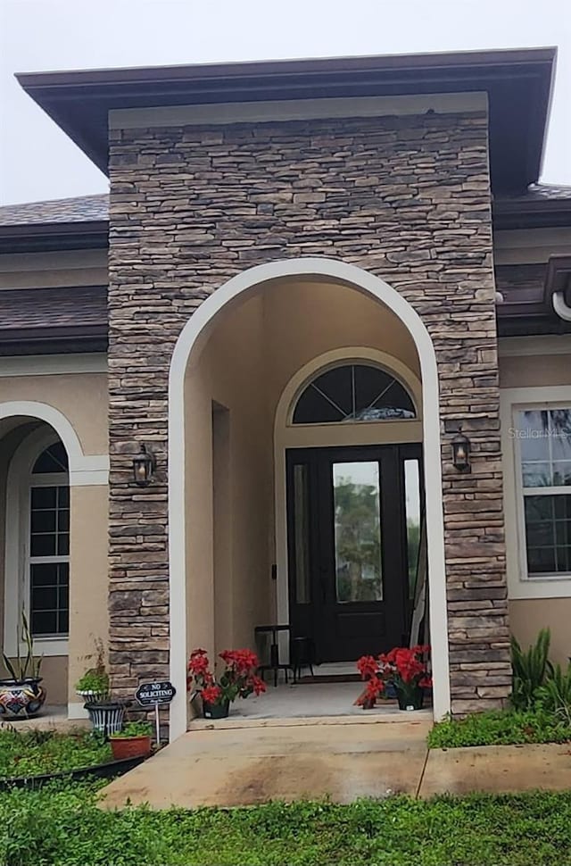 view of exterior entry with stone siding and stucco siding