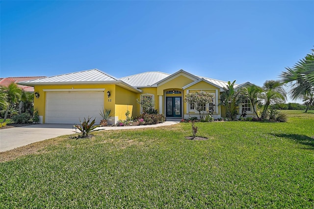 view of front of house featuring a front lawn, stucco siding, metal roof, a garage, and driveway