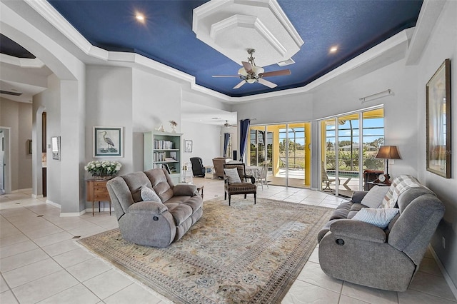 living area featuring a tray ceiling, a high ceiling, and a ceiling fan