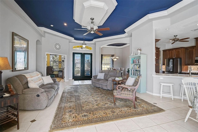 living room featuring light tile patterned floors, ceiling fan with notable chandelier, and arched walkways