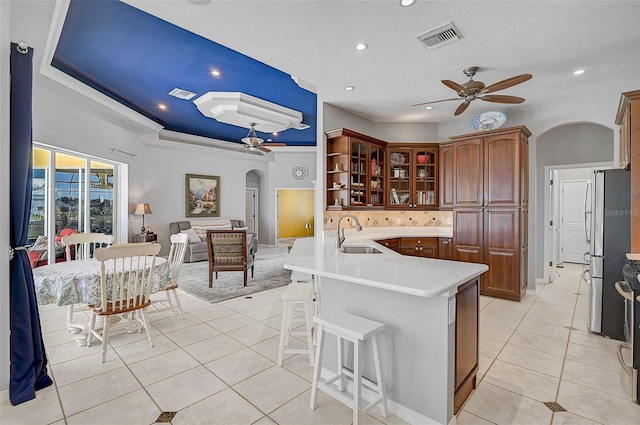 kitchen with light tile patterned floors, a ceiling fan, visible vents, arched walkways, and a sink