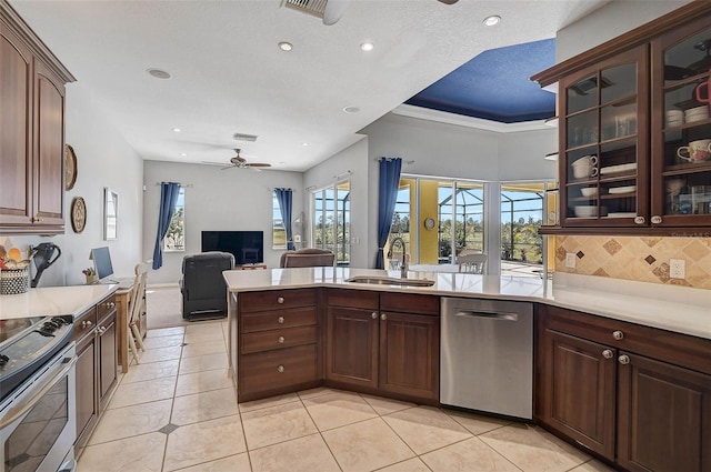 kitchen with a ceiling fan, a sink, open floor plan, stainless steel appliances, and light countertops