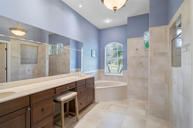 full bathroom with double vanity, a sink, tile patterned flooring, a walk in shower, and a garden tub