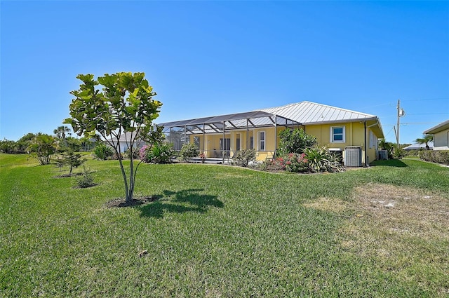 view of front of house with a lanai, central AC unit, and a front lawn