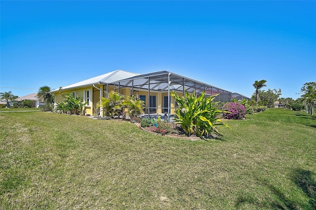 back of house featuring a yard, a lanai, and stucco siding