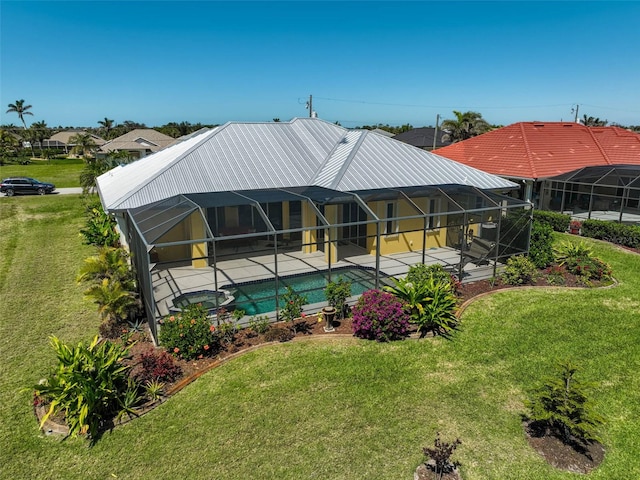 rear view of house with a pool with connected hot tub, a yard, metal roof, a lanai, and a patio area